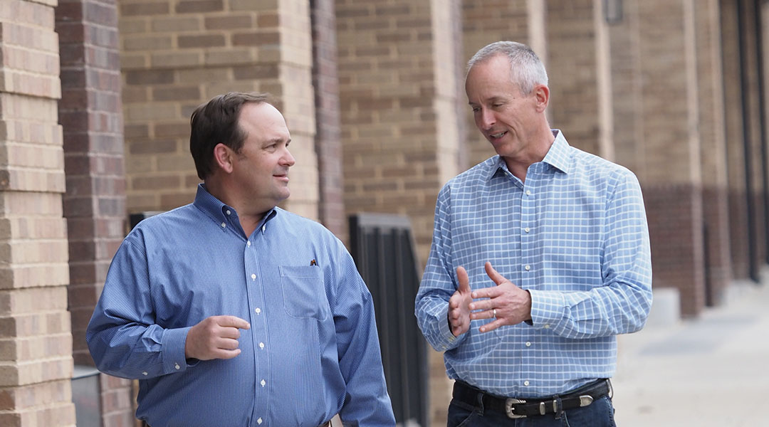 two business men walking side by side dallas texas sidewalk explaning sendero cross capital team members geoff and don commercial real estate company